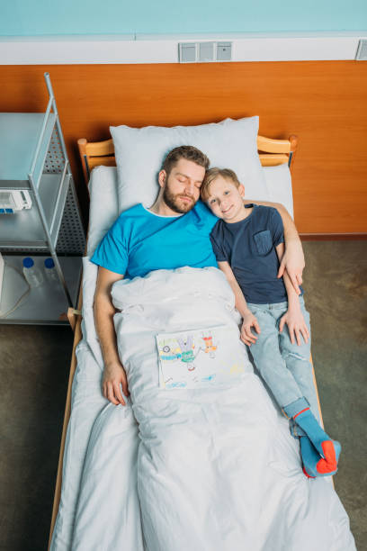 istock father with son embracing while laying on hospital bed at ward, dad and son 687018740
