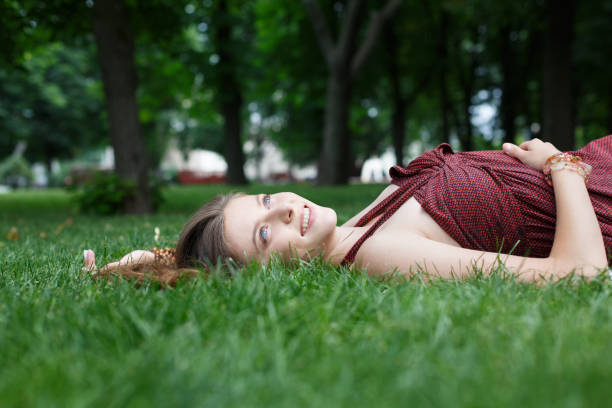 istock Beautiful young girl lying on grass in summer park 687020148