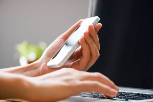 istock Finger type using laptop and phone screen, detail simple close up 687023632