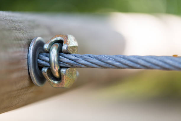 Twisted metal strong rope connected to wooden construction. Close up macro with focus on connection point with steel block