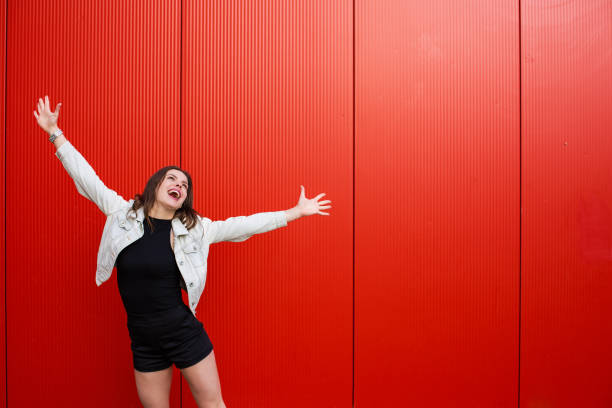 istock Stylish woman standing near red wall 687031704