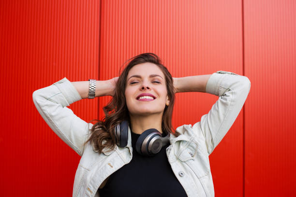 istock Stylish woman standing near red wall 687034008
