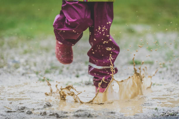istock Children in rubber boots and rain clothes jumping puddle defocused. 687037770