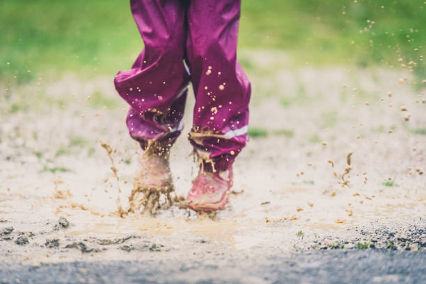 istock Children in rubber boots and rain clothes jumping puddle defocused. 687037926