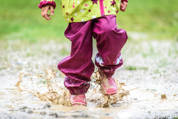istock Children in rubber boots and rain clothes jumping in puddle. 687038032