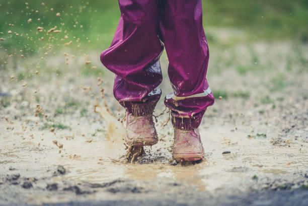istock Children in rubber boots and rain clothes jumping in puddle. 687038082