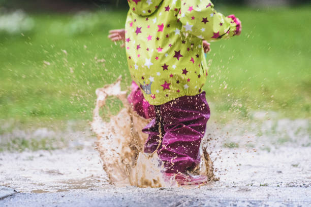 istock Children in rubber boots and rain clothes jumping in puddle. 687038140