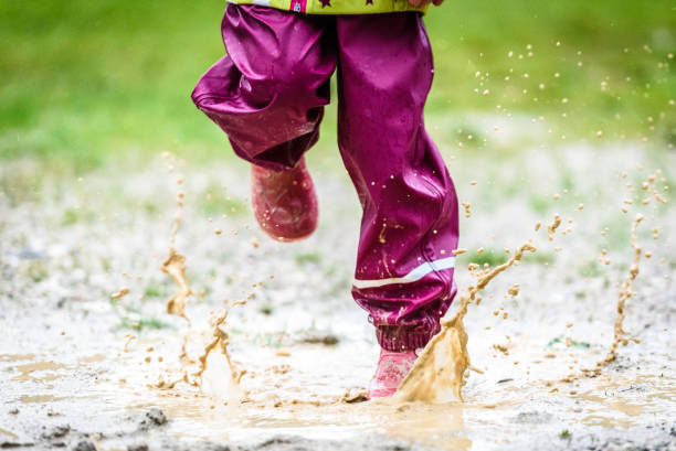 istock Children in rubber boots and rain clothes jumping in puddle. 687038198