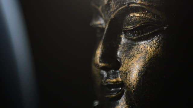 Buddha face, figure buddhist, rotating at black background with smoke