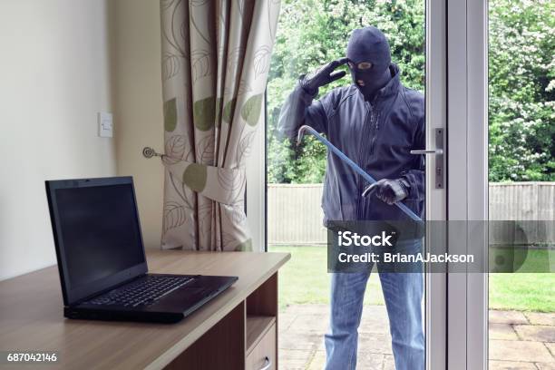 Thief Looking Through Patio Doors Window At A Laptop Computer To Steal Stock Photo - Download Image Now