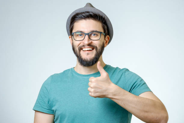 hombre feliz dando pulgar arriba signo sobre fondo gris - confidence toothy smile thumbs up ok sign fotografías e imágenes de stock