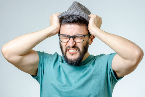 istock Young depressed handsome bearded man touching his head and having a headache over gray background 687046512
