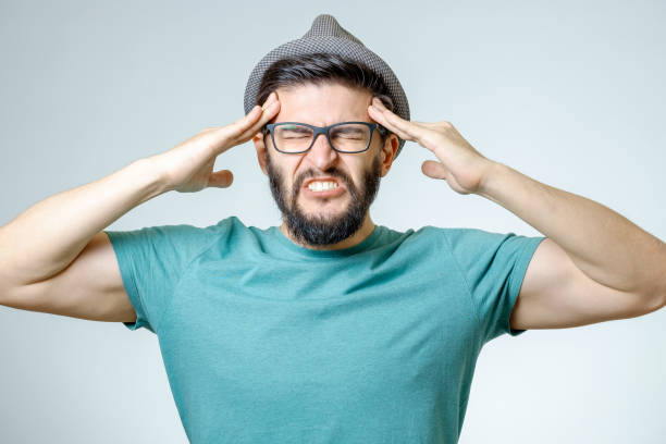 istock Young depressed handsome bearded man touching his head and having a headache over gray background 687046516