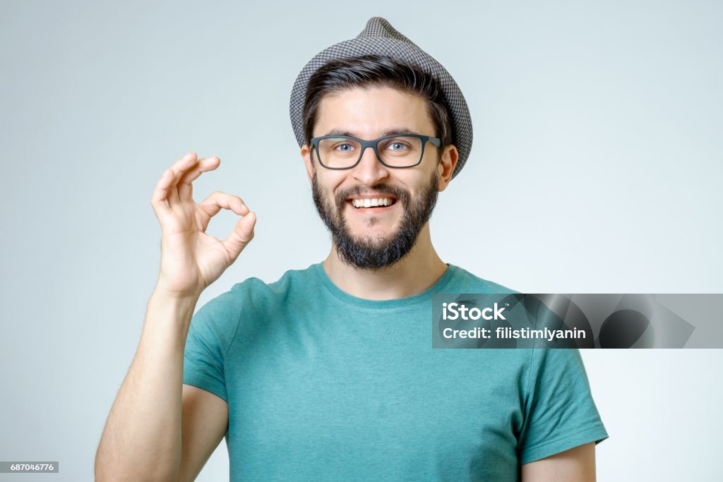 Everything is OK! Happy young man gesturing OK sign and smiling against gray background OK Sign Stock Photo