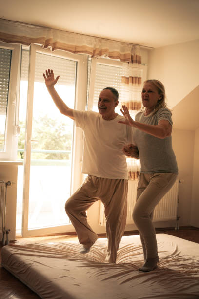 istock Senior couple dancing and jumping together on bed  holding hands. 687061362