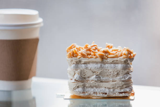 Coffee Meringue Cake  on top Almond, with disposable cup coffee selective focus at window light background.