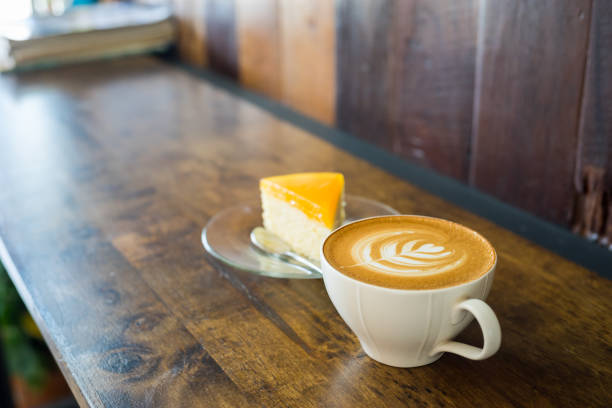 istock latte art with orange cake on wood table. 687085176