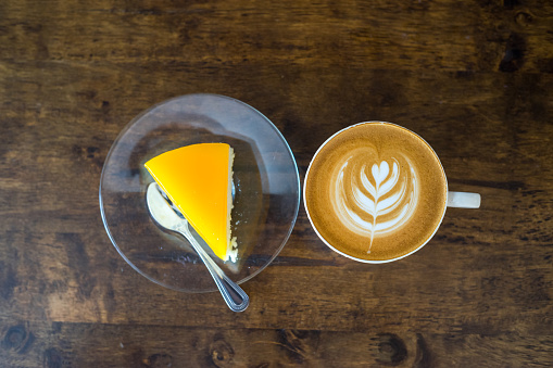 Latte Art con tarta de naranja en mesa de madera. photo