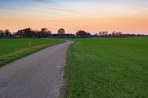 paisagem rural holandesa com estrada de pista única ao pôr do sol. - single lane road road sunset rural scene - fotografias e filmes do acervo