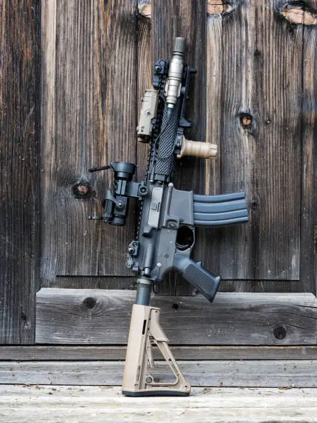 The Black Rifle. Tactical carbine beside wooden door of old house.