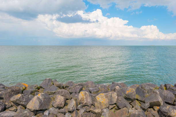 Dike of basalt stones along a lake in spring