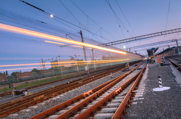 istock High speed passenger train on railroad track in motion at night. Blurred commuter train in railway platform. Railway station with blue sky. Railroad travel, railway tourism. Industrial landscape 687099958