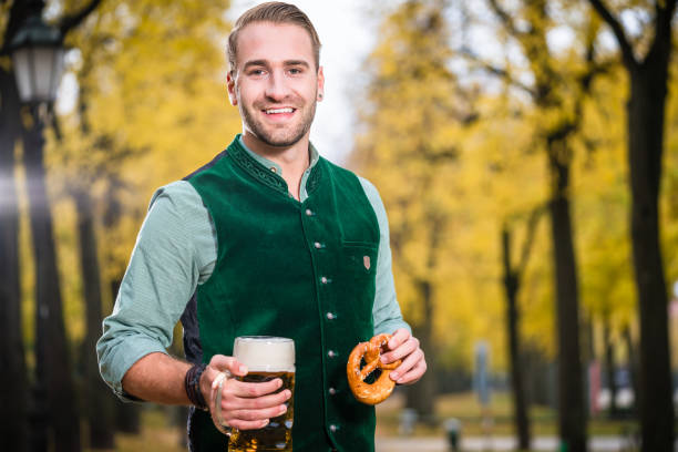 man in traditional bavarian tracht drinking beer out of huge mug - dirndl traditional clothing austria traditional culture imagens e fotografias de stock