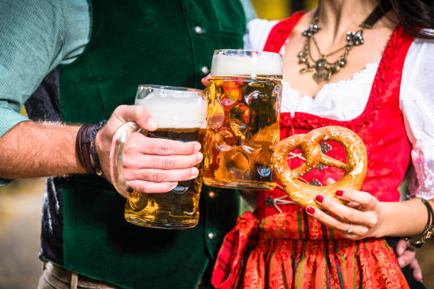 hands holding beer and pretzels, detail of bavarian tracht - dirndl traditional clothing austria traditional culture imagens e fotografias de stock