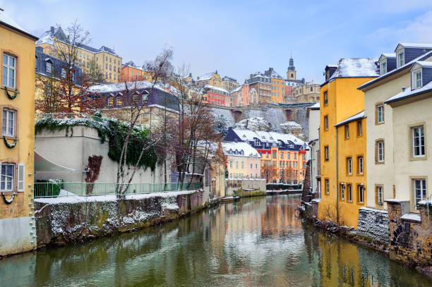 View from the Grund up to the Old Town of Luxembourg Old Town of Luxembourg and the Grund reflecting in water of Petrusse river on a snow winter day petrusse stock pictures, royalty-free photos & images