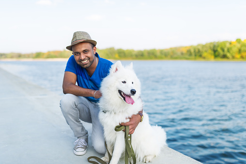 The young Sri Lankan and his fluffy dog have a rest in the park on the river bank. Portrait closeup.