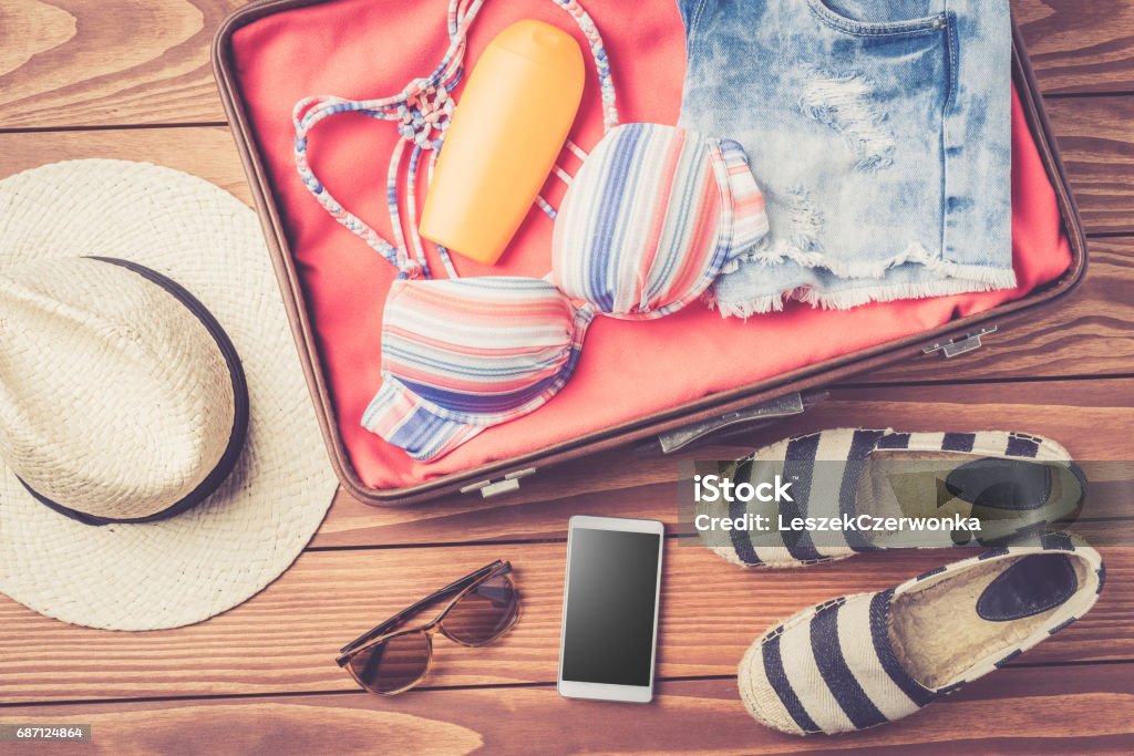 Open bag with beach accessories and clothes Open bag with beach accessories and clothes. Top view Suitcase Stock Photo