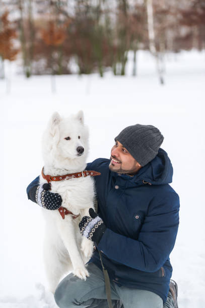 istock Young indian man and solid white fluffy dog in winter day. 687128096