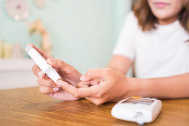 close up of asian woman hands using lancet on finger to check blood sugar level by glucose meter, healthcare medical and check up, diabetes, glycemia, and people concept - diabetes blood sugar test insulin glucose imagens e fotografias de stock