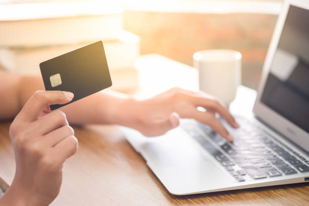 Online shopping concept. Selective focus of close up hands holding smartphone and credit card with laptop. stock photo