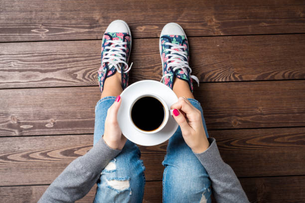 istock Woman drinking coffee while sitting on wooden floor 687151766