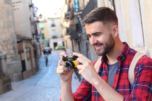 istock Handsome traveler looking at his vintage camera 687151890