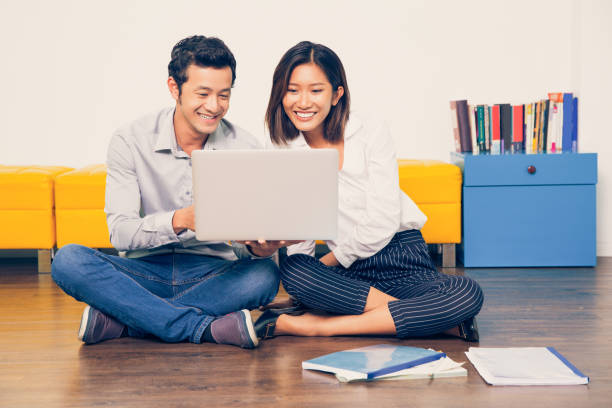 istock Cheerful couple using laptop and sitting on floor_tone 687155412