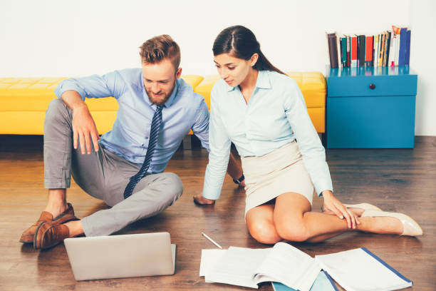 istock Young business team sitting on floor using laptop_tone 687155604