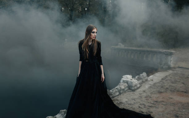 istock Young attractive Witch walking on the bridge in heavy black smoke. 687155946