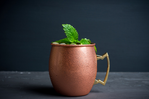 Cold Moscow Mule cocktail in copper mug on the rustic background. Shallow depth of field.