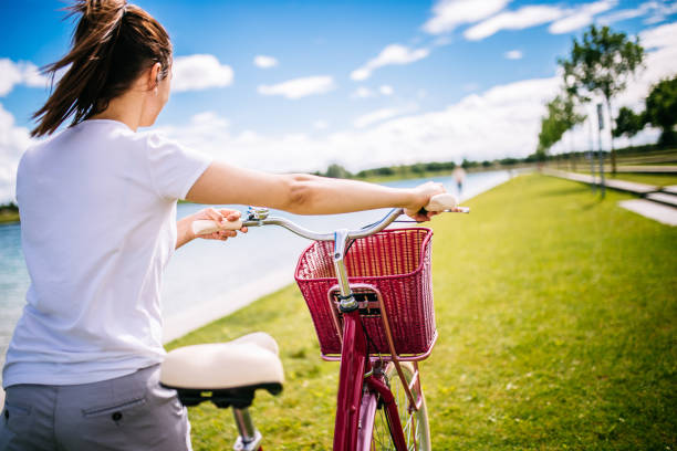 a cyclist rides a bicycle in a city park, summer day, green lawn with grass and trees, bright sunlight and shadows