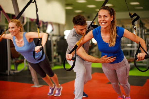 istock Personal trainer assisting young woman while exercising in the gym 687157000