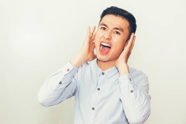 istock Closeup of Serious Young Asian Man Shouting Loud 687159574