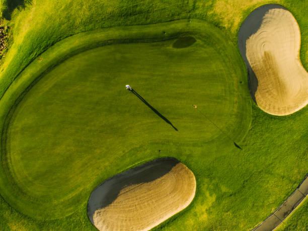 Players on a green golf course Aerial view of players on a green golf course. Golfer playing on putting green on a summer day. golf course stock pictures, royalty-free photos & images