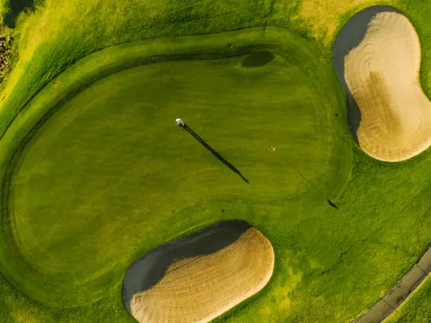 Aerial view of players on a green golf course. Golfer playing on putting green on a summer day.