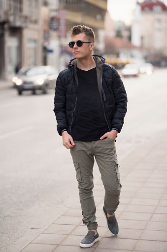 Fashion portrait of a young man walking down the city streets.