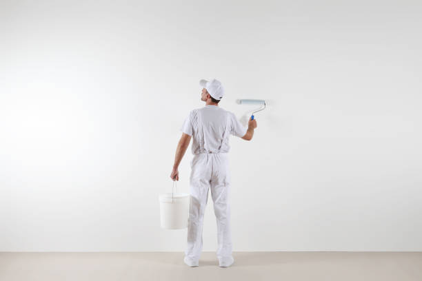 istock Rear view of painter man looking at blank wall, with paint roller and bucket, isolated on white room 687166570