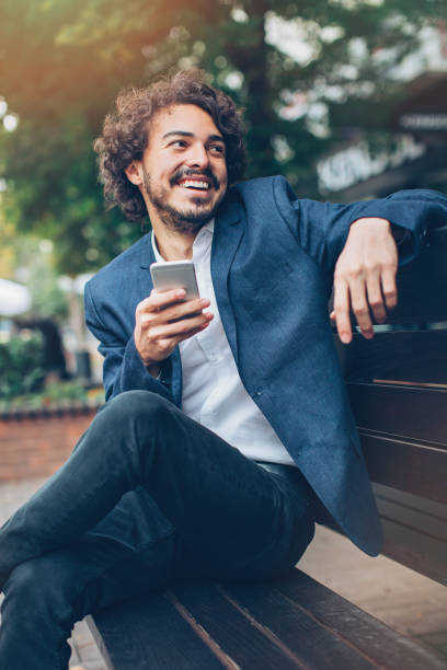 istock Young businessman with smart phone sitting in a bench 687167202