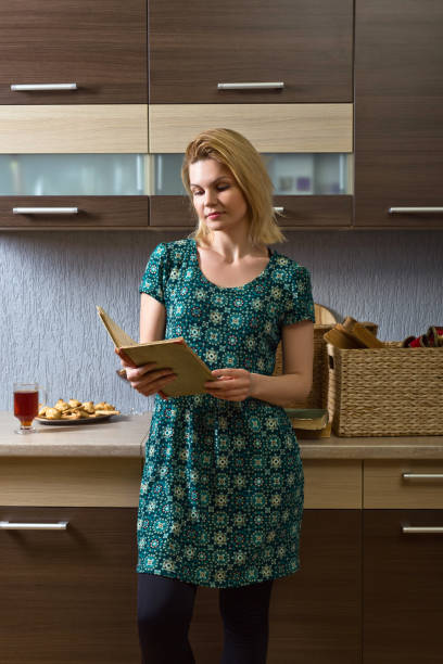 istock Young woman in green dress reading old book 687167564