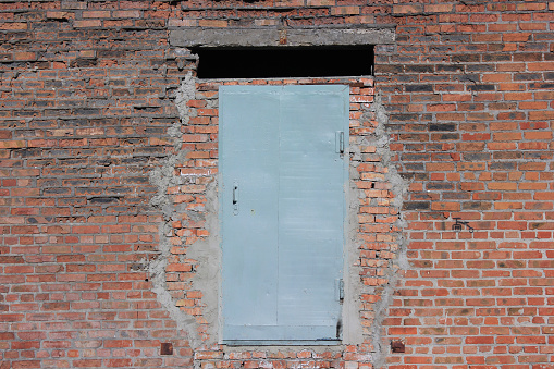 Steel door in the brick wall.the wall is very old. In the wall above the door is opening